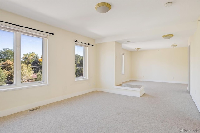 spare room with light colored carpet, baseboards, and visible vents
