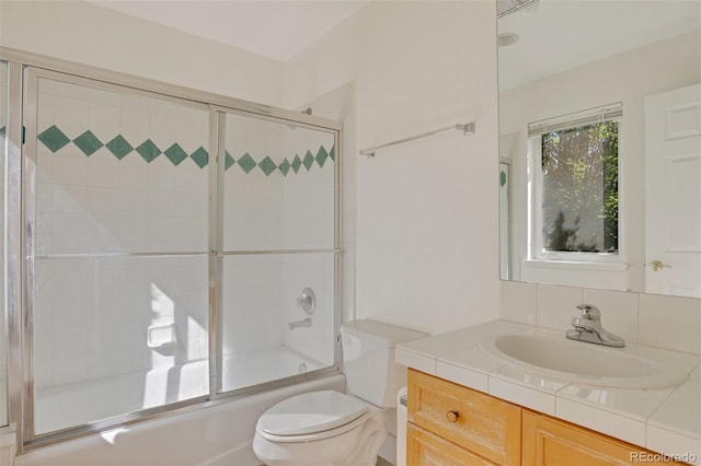 bathroom featuring toilet, enclosed tub / shower combo, and vanity