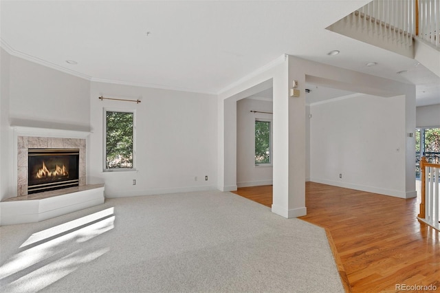 unfurnished living room with a high end fireplace, baseboards, ornamental molding, and light wood finished floors