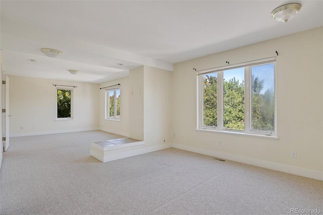 carpeted spare room featuring baseboards and visible vents