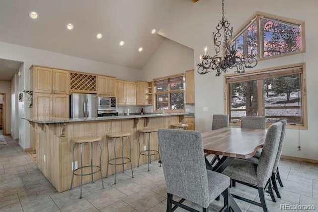 dining space featuring high vaulted ceiling, a chandelier, recessed lighting, light stone finish floors, and baseboards