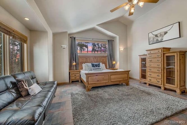 bedroom with multiple windows, stone finish floors, lofted ceiling, a ceiling fan, and baseboards