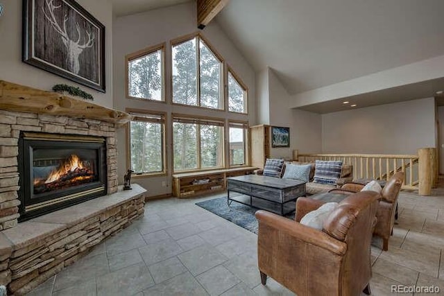 living room featuring high vaulted ceiling, a stone fireplace, stone tile flooring, and beam ceiling