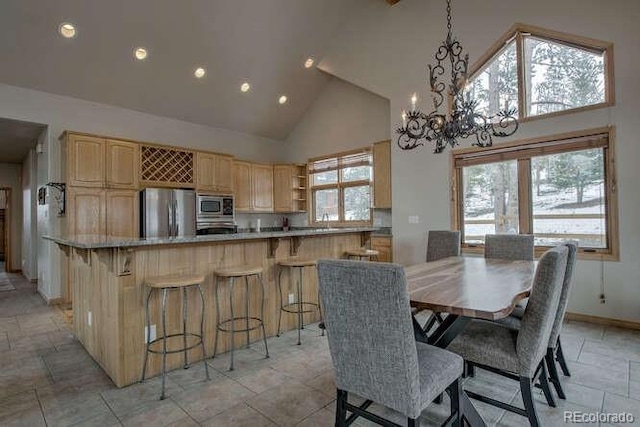 dining space featuring high vaulted ceiling, a chandelier, recessed lighting, baseboards, and light stone finish floors