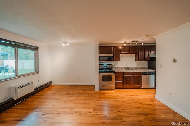 558 N Washington St Unit 103, Denver, CO 80203 - kitchen featuring appliances with stainless steel finishes, a wall unit AC, ornamental molding, light wood-type flooring, and light countertops