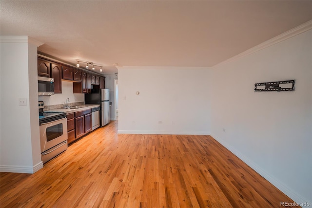 558 N Washington St Unit 103, Denver, CO 80203 - kitchen with appliances with stainless steel finishes, dark brown cabinetry, light countertops, light wood finished floors, and crown molding