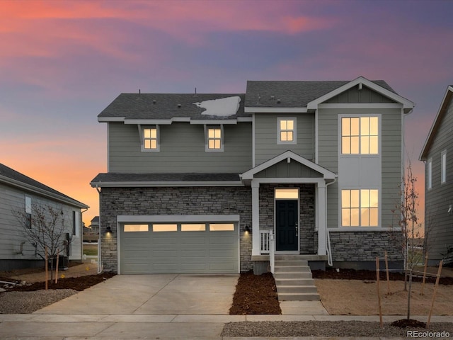 view of front of home featuring board and batten siding, roof with shingles, a garage, stone siding, and driveway