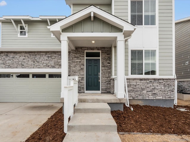 entrance to property with driveway, board and batten siding, and stone siding