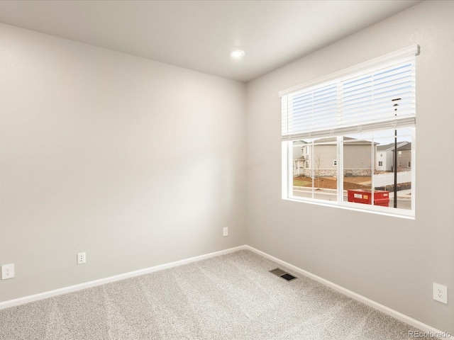 unfurnished room featuring a wealth of natural light, visible vents, baseboards, and carpet