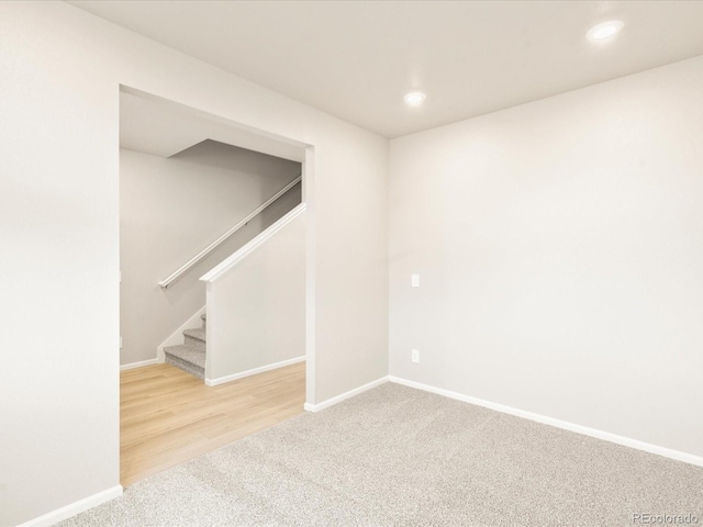 carpeted spare room with recessed lighting, baseboards, and stairs