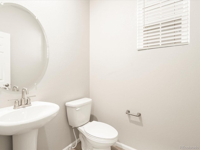 bathroom featuring toilet, baseboards, and a sink