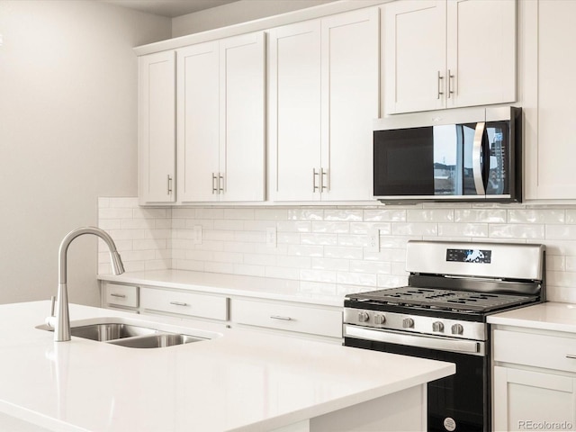 kitchen featuring backsplash, light countertops, white cabinets, stainless steel appliances, and a sink