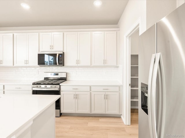 kitchen with light wood-type flooring, stainless steel appliances, light countertops, and white cabinetry