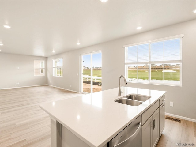 kitchen with visible vents, a sink, light countertops, light wood-style floors, and stainless steel dishwasher