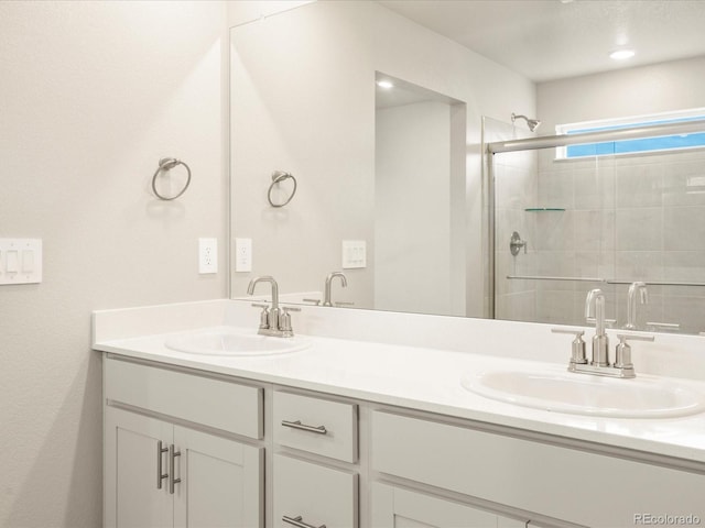 full bathroom with double vanity, a stall shower, and a sink