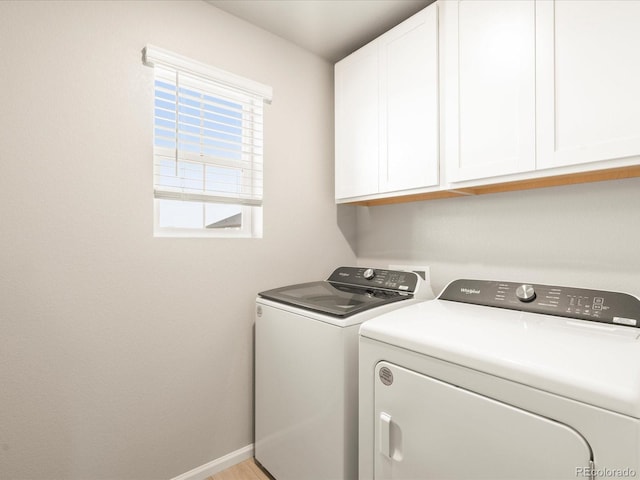 laundry room featuring washer and dryer, cabinet space, and baseboards