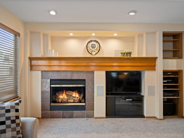 living room featuring a tile fireplace and carpet flooring