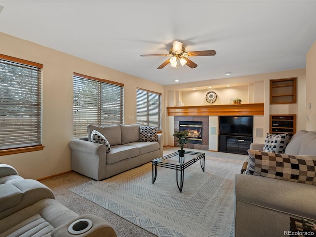 living room with built in features, a tile fireplace, ceiling fan, and carpet flooring