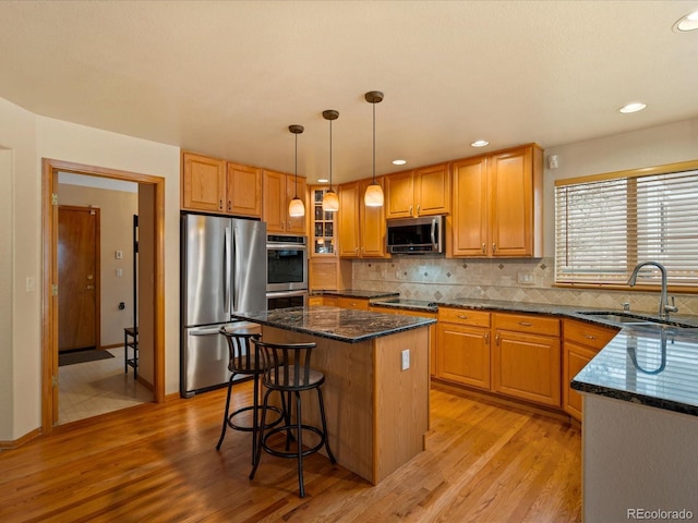 kitchen featuring a kitchen island, pendant lighting, sink, dark stone countertops, and stainless steel appliances