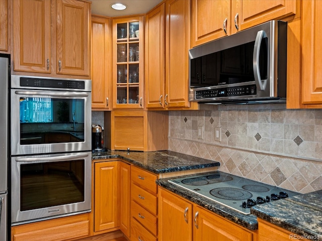 kitchen featuring decorative backsplash, dark stone counters, and appliances with stainless steel finishes