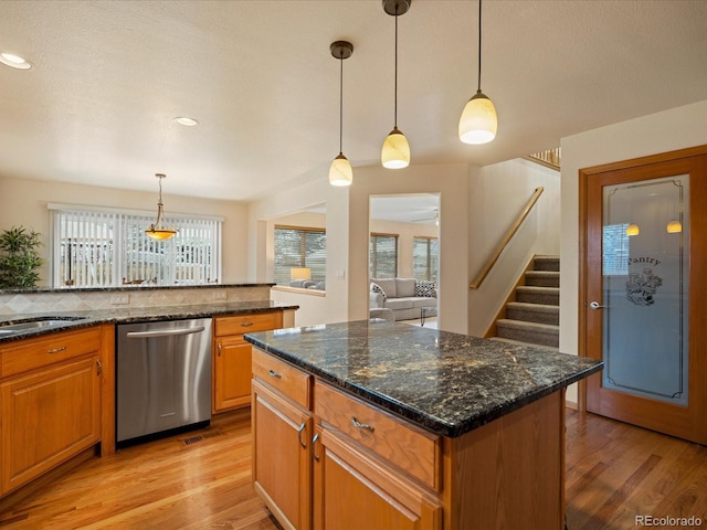 kitchen with pendant lighting, stainless steel dishwasher, and dark stone countertops