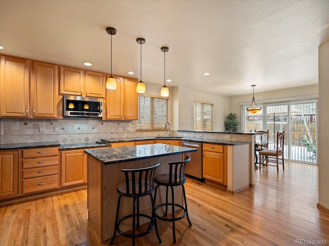 kitchen with sink, a kitchen breakfast bar, a kitchen island, pendant lighting, and stainless steel appliances