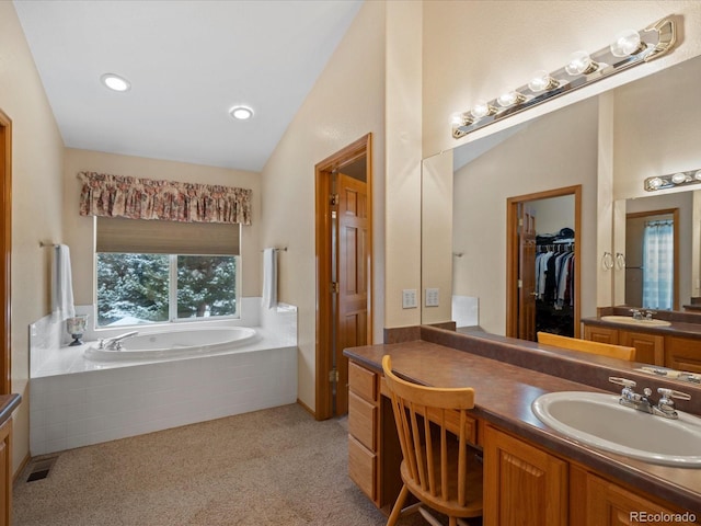 bathroom featuring tiled tub and vanity