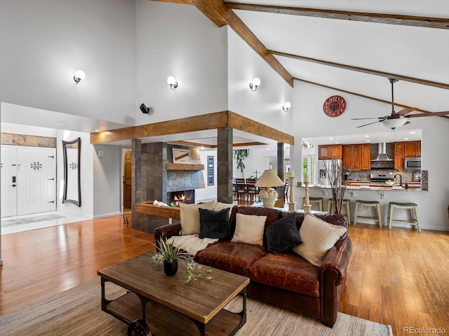 5884 S Hanover Way, Greenwood Village, CO 80111 - living area featuring high vaulted ceiling, beam ceiling, light wood-style flooring, ceiling fan, and a lit fireplace