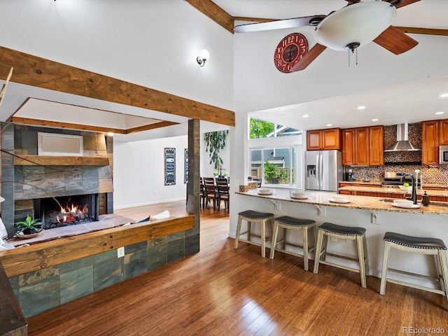 5884 S Hanover Way, Greenwood Village, CO 80111 - kitchen with appliances with stainless steel finishes, wall chimney range hood, brown cabinets, high vaulted ceiling, and a sink