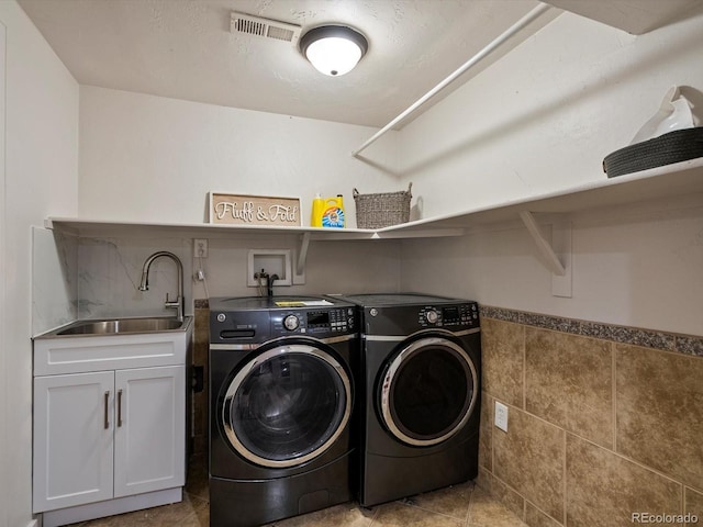 5884 S Hanover Way, Greenwood Village, CO 80111 - laundry area featuring washer and clothes dryer, cabinet space, a wainscoted wall, tile patterned floors, and tile walls