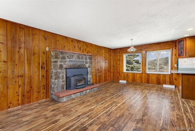 26063 Morris Ave, Conifer, CO 80433 - unfurnished living room featuring wood finished floors, wooden walls, and a wood stove