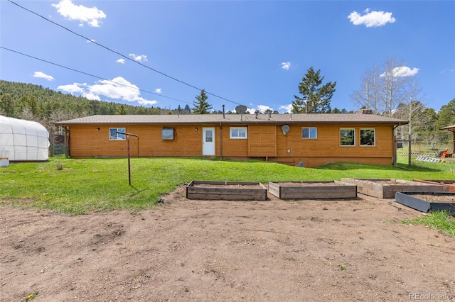 26063 Morris Ave, Conifer, CO 80433 - rear view of house featuring a vegetable garden, a lawn, and a chimney