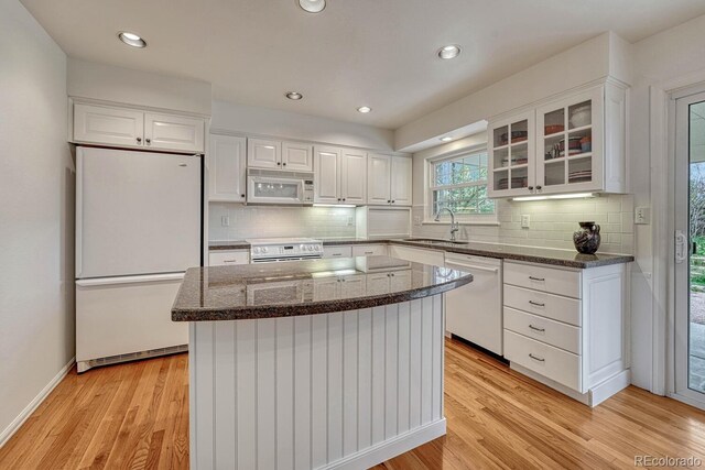 7100 S Hudson Cir, Centennial, CO 80122 - kitchen with white appliances, light wood-type flooring, dark stone counters, white cabinets, and a sink