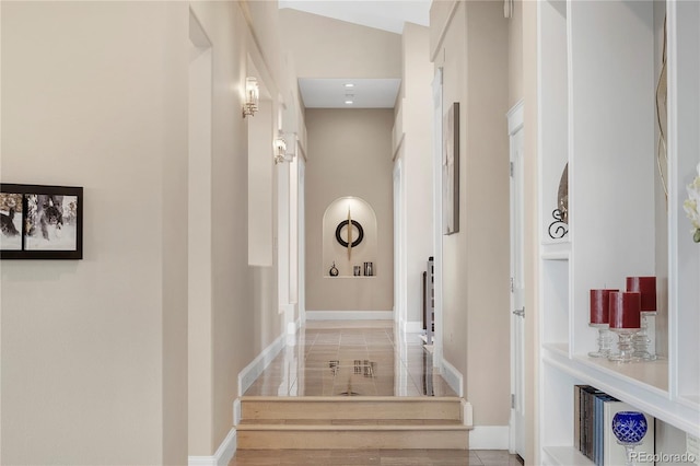 corridor with baseboards and a towering ceiling