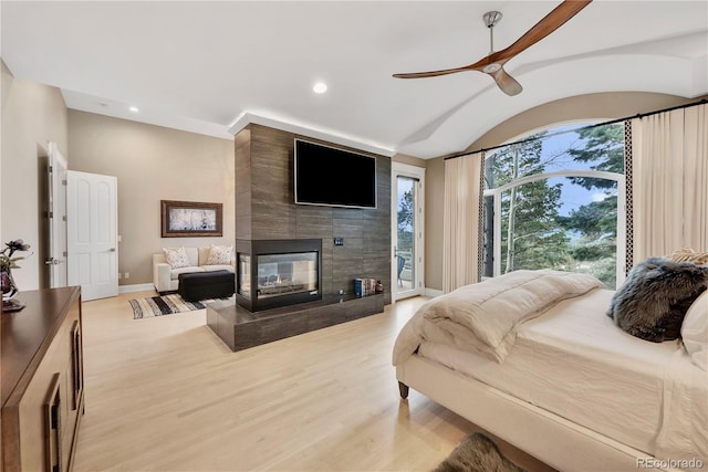 bedroom with recessed lighting, light wood-style flooring, baseboards, a tiled fireplace, and access to exterior