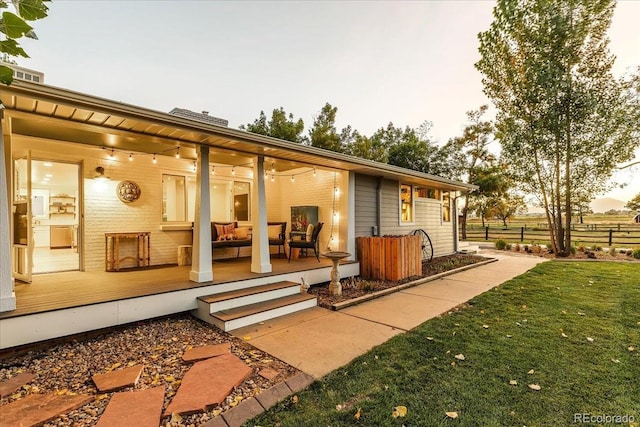 back house at dusk featuring a wooden deck and a yard