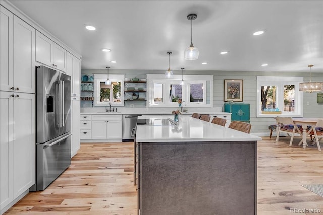 kitchen with stainless steel appliances, white cabinetry, plenty of natural light, and decorative light fixtures