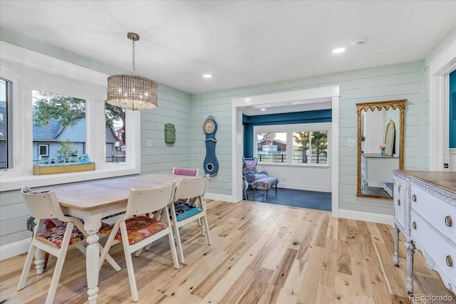 dining area featuring a chandelier, light hardwood / wood-style floors, and wood walls