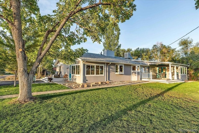 back of property with central AC unit and a lawn