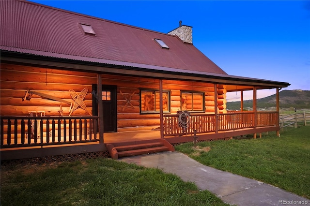 rear view of property featuring a chimney, a yard, a mountain view, log siding, and metal roof