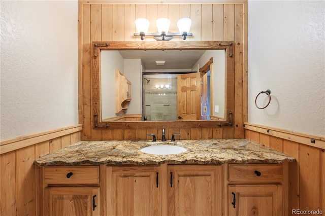 bathroom featuring vanity, a wainscoted wall, and a textured wall