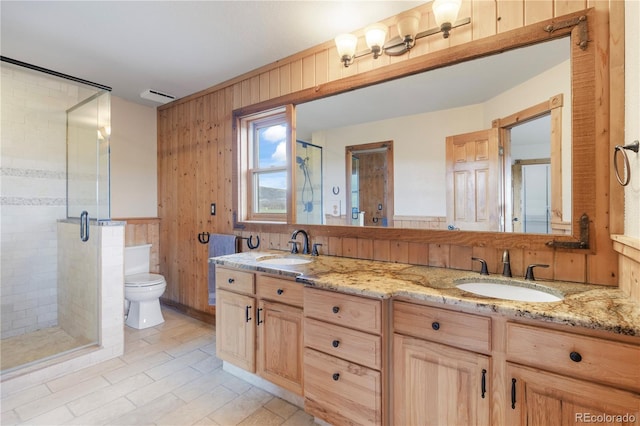 full bath with a sink, double vanity, toilet, and a shower stall