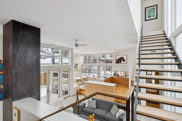 living room featuring a towering ceiling, stairway, and a ceiling fan