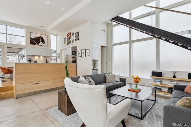 living area featuring concrete flooring, a towering ceiling, and recessed lighting