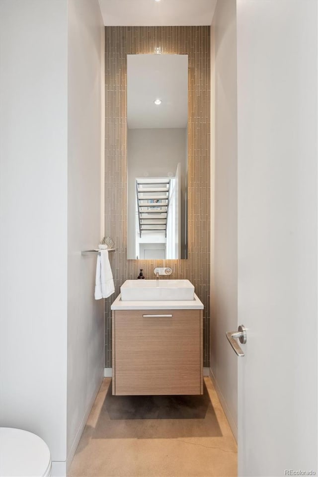 bathroom featuring toilet, vanity, and baseboards