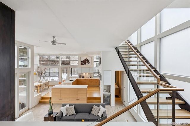 interior space featuring light tile patterned floors, floor to ceiling windows, stairway, and a ceiling fan