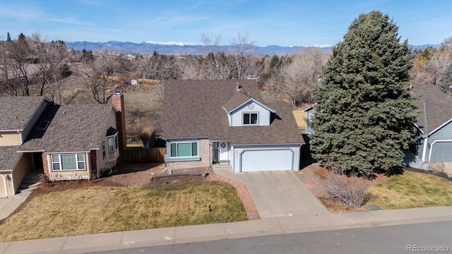 view of front of home with a mountain view, a chimney, concrete driveway, a front lawn, and brick siding