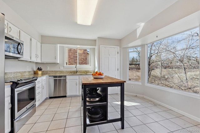 kitchen featuring white cabinetry, light tile patterned floors, appliances with stainless steel finishes, and a sink