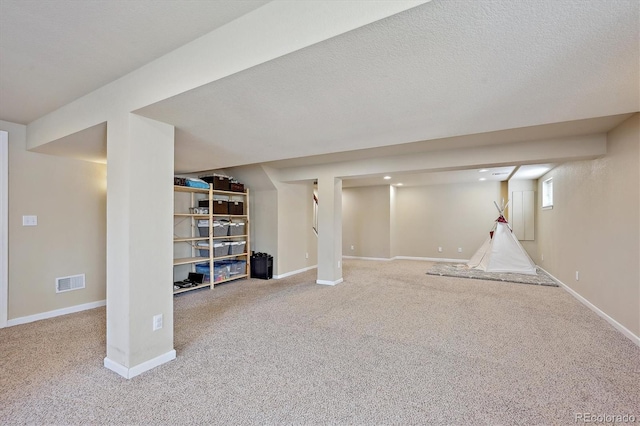 finished basement with visible vents, carpet flooring, a textured ceiling, and baseboards