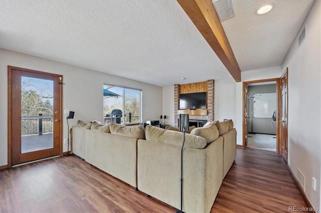 living room with a fireplace, visible vents, and dark wood-style flooring